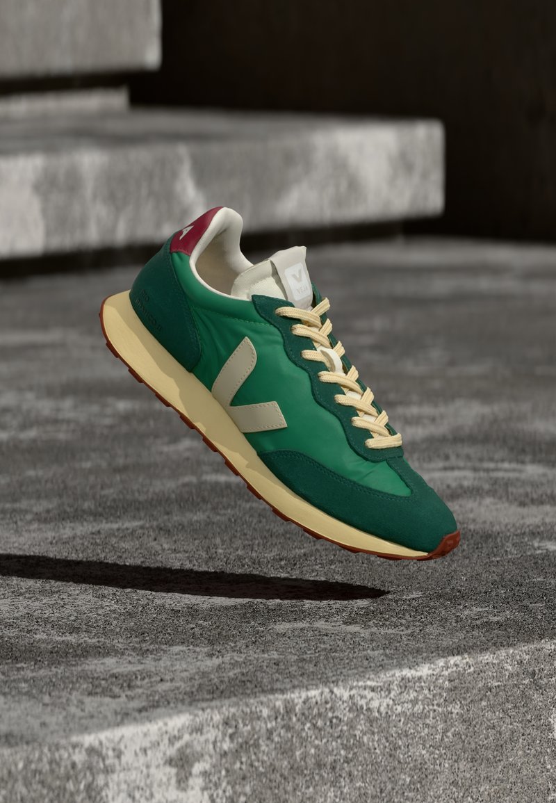 Πράσινο και κρεμ αθλητικό παπούτσι με υφασμένο επάνω μέρος, αντίθετη μπορντό φτέρνα, κρεμ κορδόνια και λαστιχένια σόλα. Διαθέτει εμφανές λογότυπο στο πλάι.