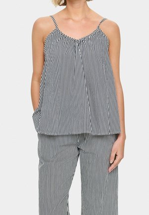 Woman wearing black and white vertical striped sleeveless top with thin straps and matching striped pants.