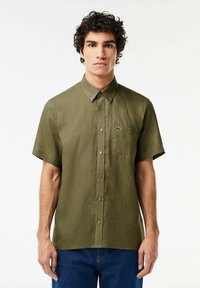 Camicia a maniche corte con bottoni color verde oliva, in tessuto texture, con taschino con logo e colletto abbottonato.