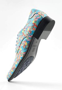 Chaussure lacée colorée ornée d'un motif floral bleu, avec une semelle en caoutchouc noir et une texture lisse, dotée d'un petit talon surélevé et d'un design de semelle unique.
