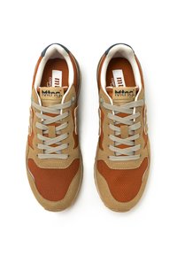 Zapatillas marrones y beige con parte superior de malla y ante, diseño sin cordones y cordones beige. Presenta un logo sutil en la lengüeta y en los laterales.