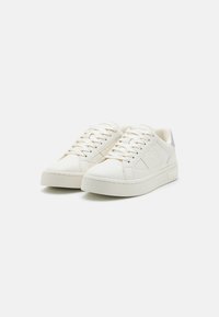 White leather sneakers with a smooth texture, featuring a low-top design, round toe, and flat rubber sole. Subtle branding on the side.