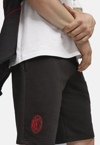 Sorte shorts lavet af blødt stof, med et klart rødt AC Milan-logo. Har sidelommer og en afslappet pasform.