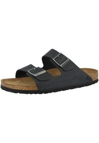 Svart sandal med två justerbara remmar och silverfärgade spännen, kork fotbädd och gummisulor. Har en platt, öppen tådesign.