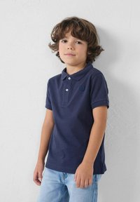 Navyblauwe poloshirt met korte mouwen, een kraag en drie witte knopen. Bevat een subtiele logodetail op de borst. Gemaakt met lichtblauwe spijkerbroeken.