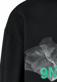 Felpa nera con stampa grafica di una texture argentata spiegazzata e il numero "9N" in turchese. Presenta polsini a coste e una vestibilità rilassata.