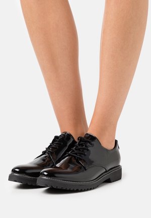 Zwarte lakleren schoenen met een glad oppervlak, ronde neus en lage rubberen zool. Voorzien van zwarte veters en minimale stiksels.