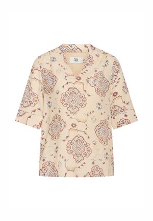 Blusa corta a maniche corte color crema con scollatura a V. Presenta ornate fantasie geometriche rosse e blu e una vestibilità rilassata.