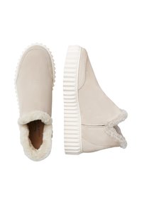 Beige instap schoenen met een gestructureerde buitenkant, witte ribbelzool, en een zachte bontvoering bij de enkel. Geen zichtbare veters of sluitingen.