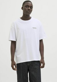 Hvid bomulds T-shirt med et grønt trykt logo "NATURE'S WORLD OF ART" på venstre bryst, kortærmet og med en afslappet pasform.
