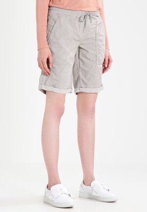 Persona vistiendo pantalones cortos gris claro hasta la rodilla con puños enrollados, bolsillos delanteros tipo parche, cintura con cordón, parte superior de manga larga rosa y zapatillas blancas.