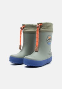Botas de goma verdes e impermeables con una suela azul texturizada, cordón naranja ajustable y un logo circular con montañas.