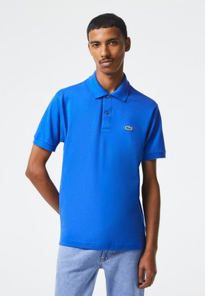 Polo blu in un tessuto testurizzato, con colletto, patta con tre bottoni e un piccolo logo di coccodrillo verde sul petto.