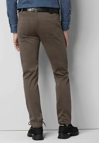 Pantalons marron avec une texture lisse, coupe droite et deux poches arrière. Associés à des baskets en mesh noires et une chemise en denim bleue.