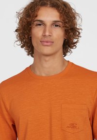 Herrers orange langærmet t-shirt lavet af struktureret stof med rund halsudskæring og en venstre brystlomme med et broderet logo.