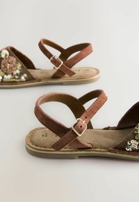 Sandali marroni con una morbida finitura in suede, dotati di fasce incrociate e fibbie regolabili. Decorati con ricami floreali e paillettes.