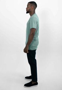 Mintgroene t-shirt met korte mouwen, relaxed fit, gecombineerd met donkere broeken en zwarte instappers. Eenvoudig ontwerp, gladde textuur.