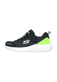 Scarpa sportiva nera con tessuto impermeabile, dettagli verdi, una fascia in Velcro e una suola bianca testurizzata con motivi a onda.