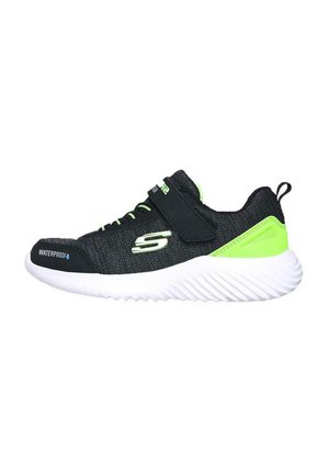 Zapatilla deportiva negra con tejido impermeable, detalles en verde, una correa de Velcro y una suela blanca texturizada con patrones en forma de ola.