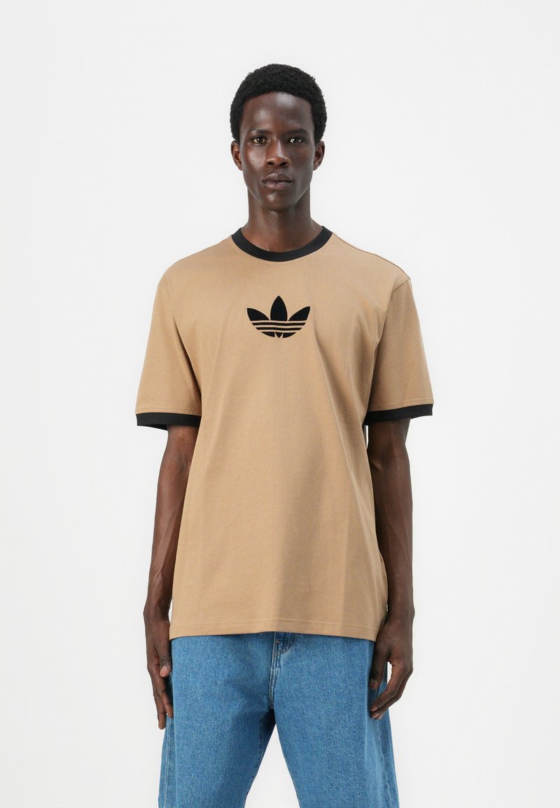 Rudas trumpas rankovės marškinėliai su juodu įsiūtu apykaklės ir rankovių klokeliu. Centrinėje krūtinės dalyje yra juodas adidas logotipas.