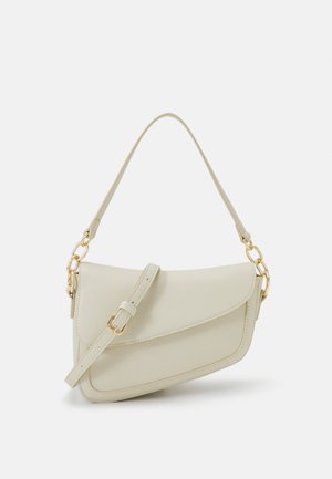 Small cream handbag with a textured finish, a long adjustable strap, a chain accent, and a flap closure. Gold hardware detailing.