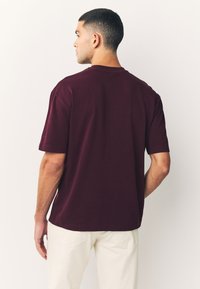 Bordeauxrood katoenen T-shirt met korte mouwen en een ronde hals, met een losse pasvorm en effen kleur zonder patronen of accenten.