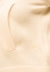 Πλεκτό πουλόβερ εκρού με ριμπ V-λαιμόκοψη και διακριτικό κεντημένο λογότυπο στο στήθος.