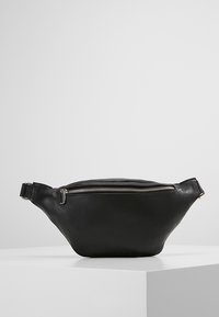 Marsupio in pelle nera con forma curvata, chiusura superiore con zip e una tracolla regolabile. Texture liscia con dettagli di cucitura discreti.