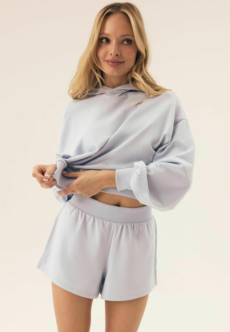Jasnofioletowa bluza z kapturem i szerokimi rękawami, w zestawie z dopasowanymi szortami z elastycznym paskiem w talii i luźnym krojem.