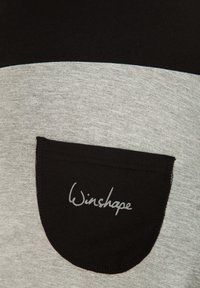 Siva in črna majica s krožnim črnim žepom, ki vsebuje "Winshape" logo v sivi pisavi. Gladka tekstura, sproščen dizajn.