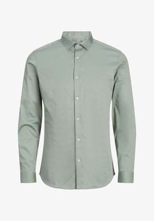 Camisa de manga larga verde claro hecha de una tela suave, con un collar puntiagudo, cierre de botones en la parte delantera y un dobladillo curvado.