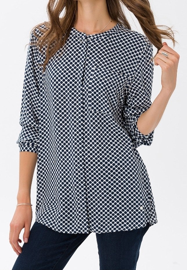 Blusa a pois blu navy e bianca con colletto rotondo, chiusura a bottoni e maniche a tre quarti. Tessuto morbido con una vestibilità comoda.