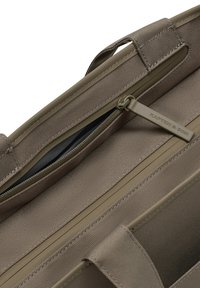 Bruine stoffen tas met textuur, voorzien van een ritspocket, een Kapten & Son merktrekker en versterkte stiksels langs de randen en handvatten.