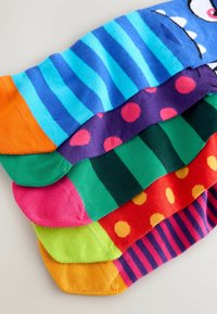 Calcetines coloridos en varios diseños: rayas azules y turquesas, morado con lunares rosas, rayas verdes, rojo con lunares amarillos y naranja.