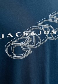 Granatowa bawełniana koszulka z białym graficznym napisem "JACK&JON" oraz wytłoczonymi literami 3D, o gładkiej fakturze i prostym designie.