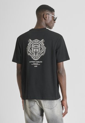 T-shirt nera in cotone con una stampa dettagliata di una tigre sul retro. Maniche corte, vestibilità comoda e scollatura rotonda.