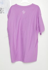 Fialové tričko Nike s krátkým rukávem, měkkou texturou, zakřiveným výstřihem a logem vytištěným na horní části zad. Strojově šité zakončení a švy.