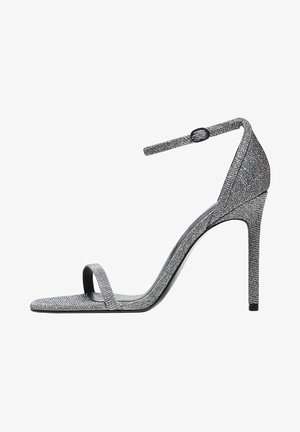 Sølv højhælet sandal med en slank ankelrem, åben tå design og tekstureret overflade. Har en spids tå og stiletto hæl.