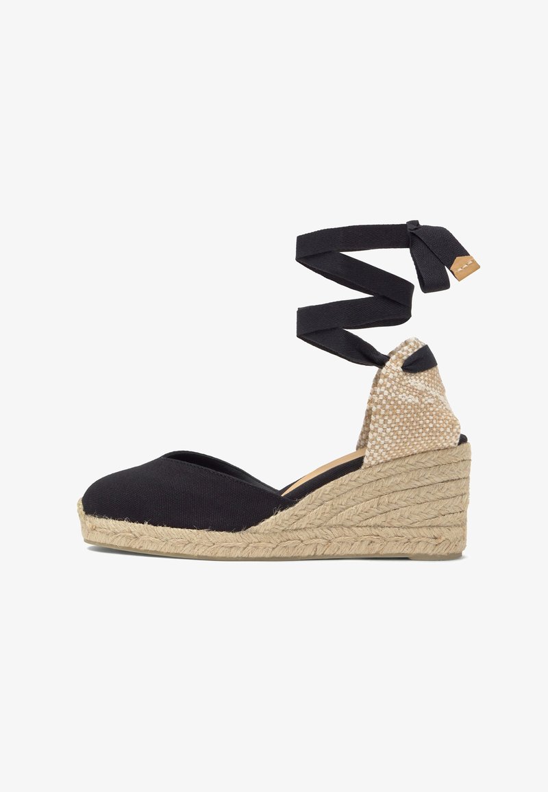 Espadrille compensée en toile noire avec semelle en jute tressée beige et long ruban noir à nouer autour de la cheville.
