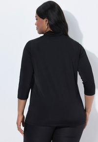Zwarte, rekbare longsleeve top met een hoge hals en driekwartmouwen. Glad textuur, getailleerd ontwerp en gebogen zoomdetail.