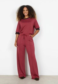 Set de îmbrăcăminte casual roșu, format dintr-un top cu mânecă scurtă și accente negre și pantaloni lejeri. Confecționat dintr-un material moale pentru confort.