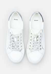 Baskets blanches avec une tige en cuir lisse, des accents argentés, des côtés texturés et des embellissements en perles sur les lacets. Nom de la marque "Bata" visible.