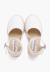 Chaussures espadrilles blanches à bout rond, avec des accents tissés beige et une bride réglable à la cheville. Semelle intérieure texturée avec étiquette logo.
