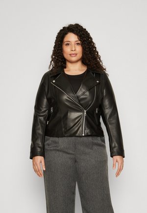 Giubbotto in pelle nera da biker con chiusura a zip e tasche, caratterizzato da un design asimmetrico e una texture liscia. Abbinato a pantaloni grigi.