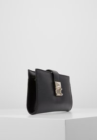 Mustavahainen lompakko, jossa on metallinen geometrinen solki. Ominaisuudet: sileä pinta ja minimalistinen muotoilu. Kompakti muoto, ohut profiili.