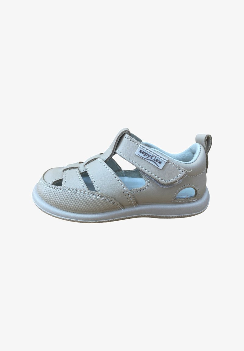 Sandalia infantil de cuero beige con cierre de Velcro etiquetado como "zapyflex", interior acolchado y diseño recortado sobre fondo blanco.