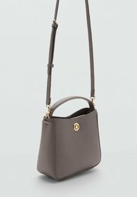 Siva kožna torba s zlatnim detaljima, kratkom ručkom i podesivim remenom. Glatka tekstura i strukturirani dizajn.