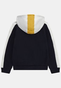 Sudadera navy con mangas blancas, capucha blanca que presenta una franja amarilla vertical centrada, y puños y dobladillo acanalados.