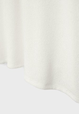 Biely textúrovaný materiál s viditeľným lemom v spodnej časti, mäkko splývajúci na jednoduchom svetlom pozadí.