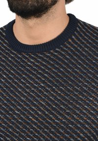 Marineblauer Strickpullover mit einem strukturierten diagonalen Muster in Grautönen und Orange, ausgestattet mit einem gerippten Kragen und weichem Stoff.